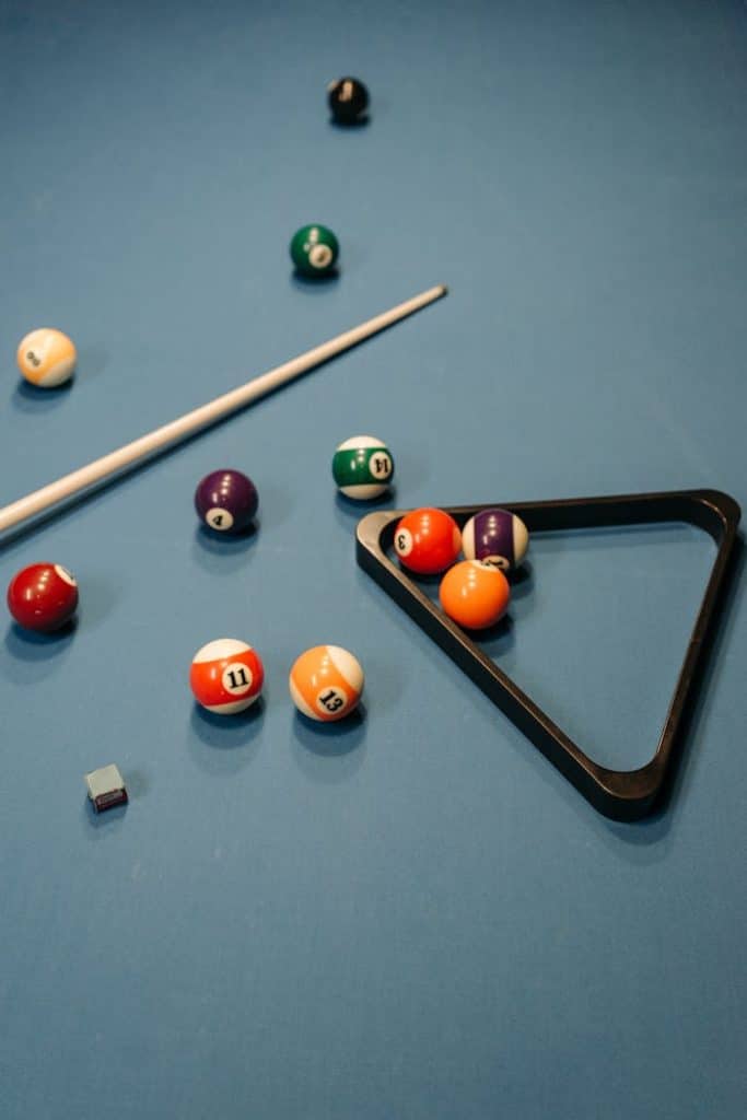 Vibrant billiard balls and cue on a pool table with chalk and rack.