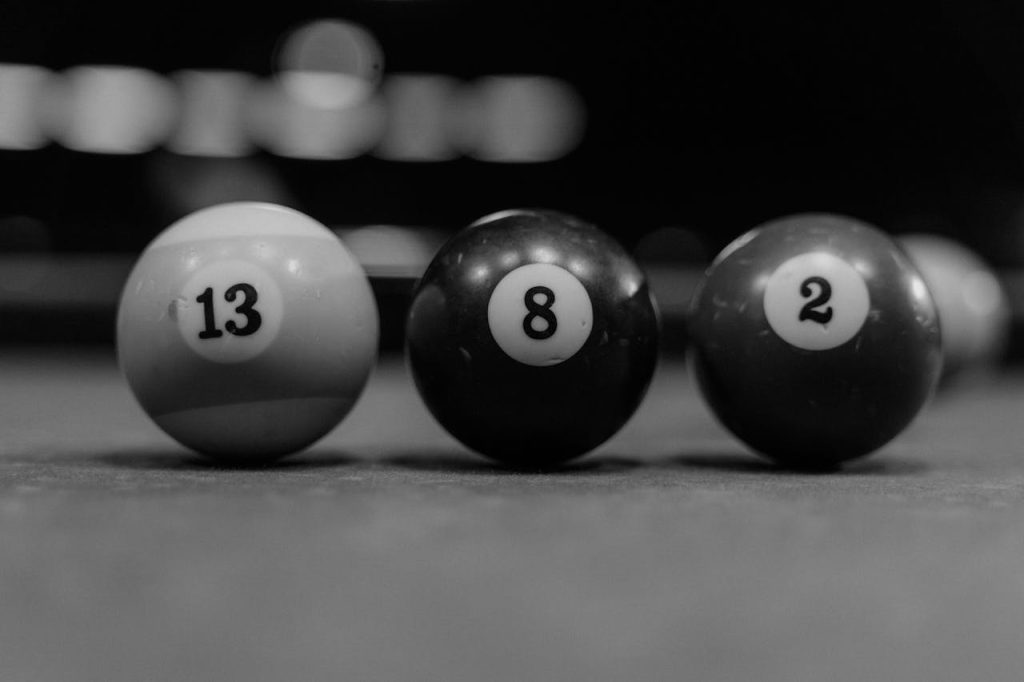 A black-and-white close-up shot of billiard balls 13, 8, and 2 on a pool table, showcasing depth of field.
