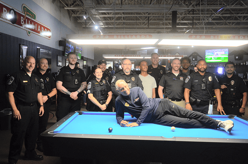 Heights law enforcement team gathers with billiards pro Jimmy Wetch inside Jimmy’s Pro Billiards for a community event
